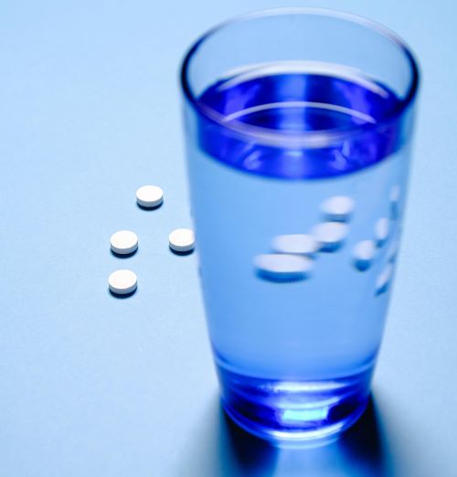 Round pills and a glass of water