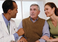 Older man with a younger woman talking to a doctor