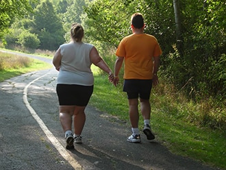 A couple walking outdoors on a sunny day.