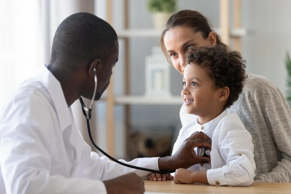 Mother holding child while a pediatrician listens to the child’s heart with a stethoscope.