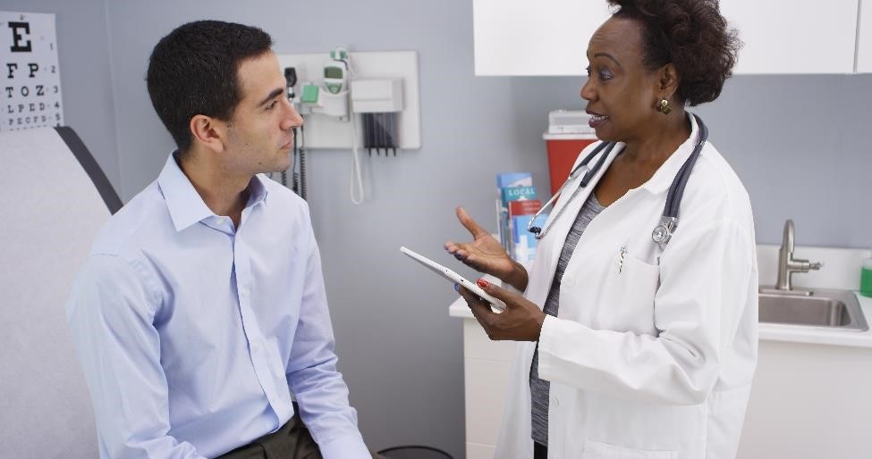 Doctor talking with a patient who is sitting on an exam table.