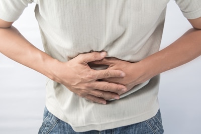 Photo of a person holding two hands against the stomach.