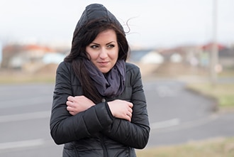 Woman with a coat shivering outdoors