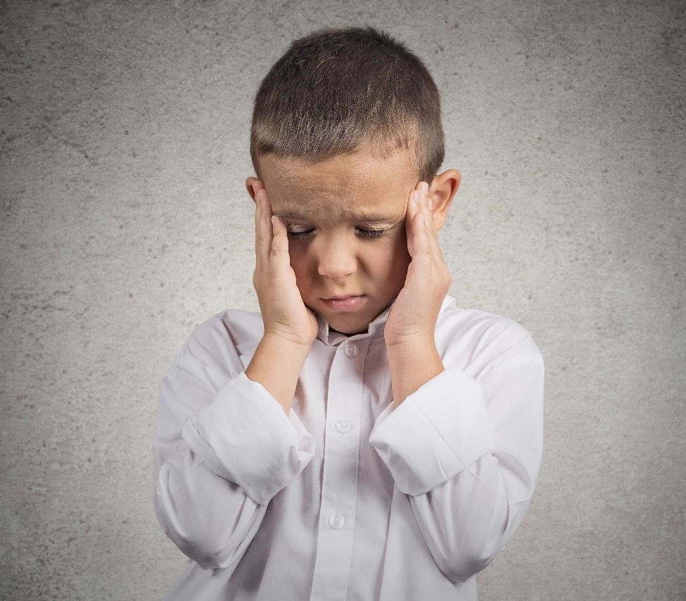 Child holding his temples in pain.