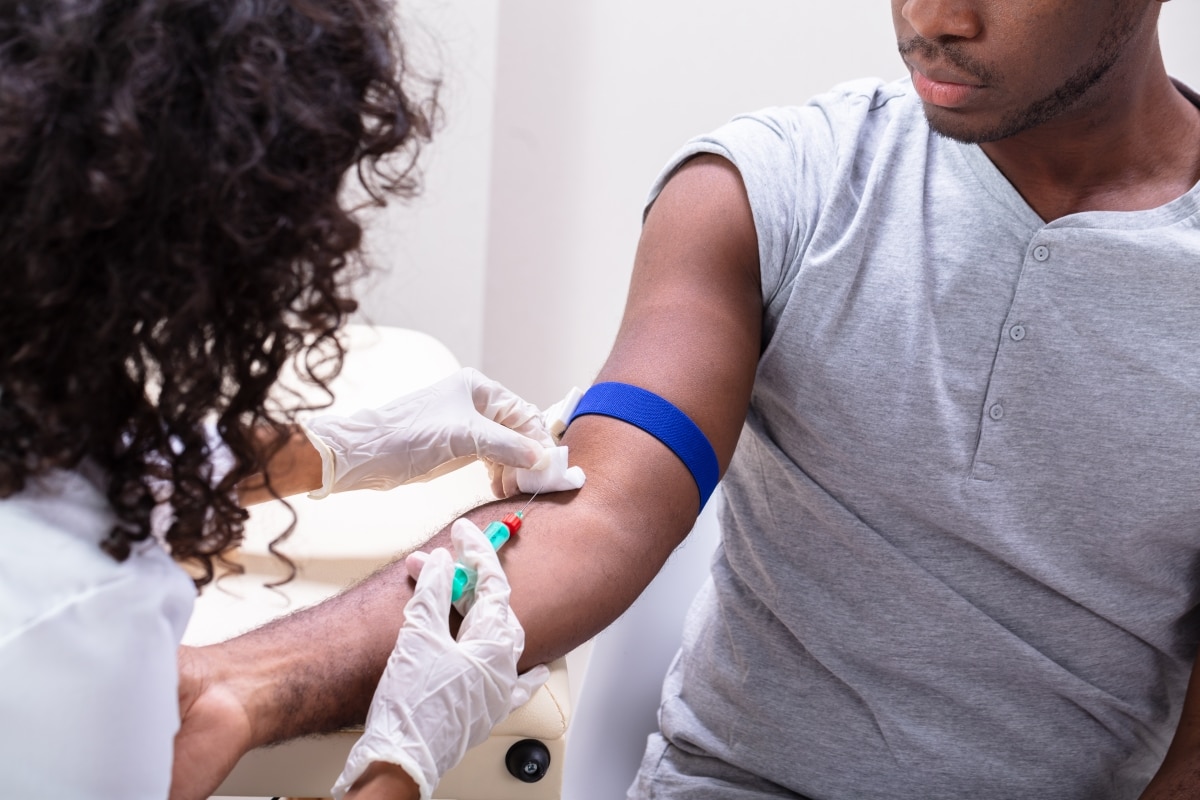 Health care professional taking a blood sample from the arm of a patient.