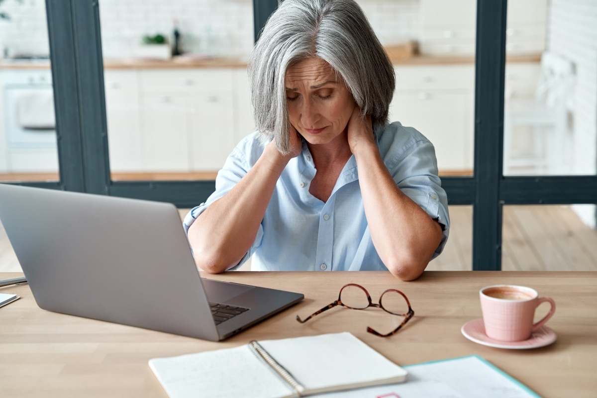 Mujer cansada sentada frente a una computadora portátil.