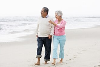 A man and a woman walk on a beach.