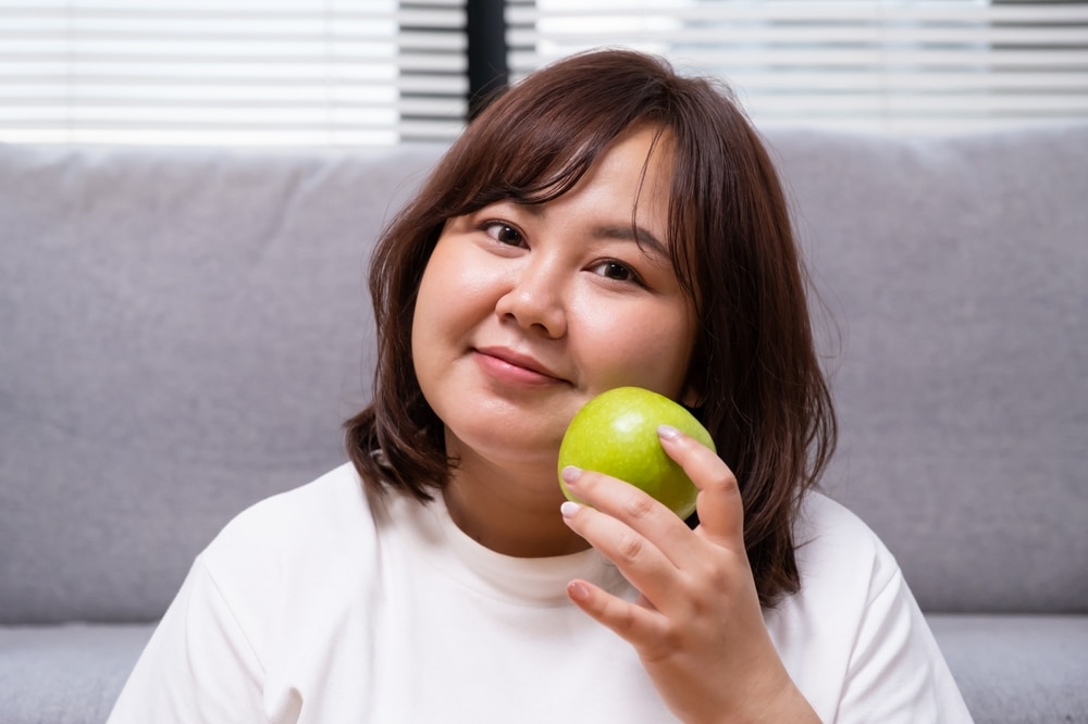A teenage girl holding a green apple.