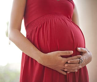 Photo of a pregnant woman holding her stomach.