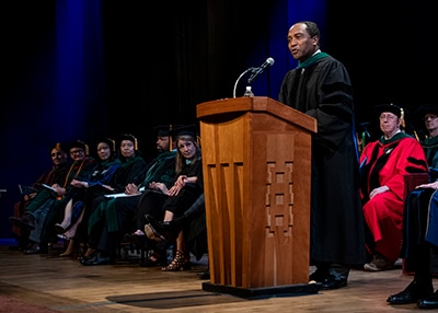 Photo of : Dr. Griffin P. Rodgers delivering the keynote address at George Washington University’s 2018 M.D. Diploma Ceremony.