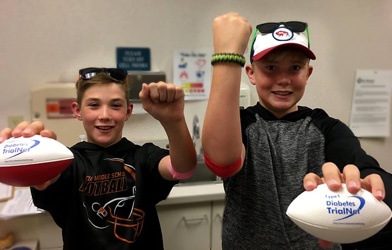 Two brothers hold Type 1 Diabetes TrialNet labeled footballs.