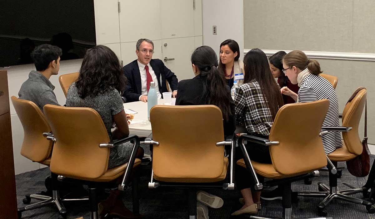 A group of people sit and talk at a round table.