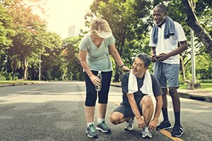 Group of people getting ready to run with one tying their shoe.