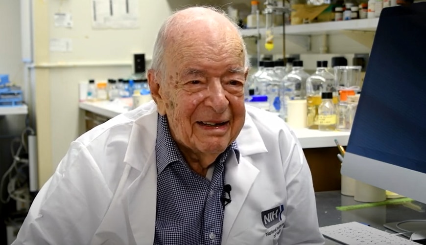 Dr. Herbert Tabor being interviewed in a lab.