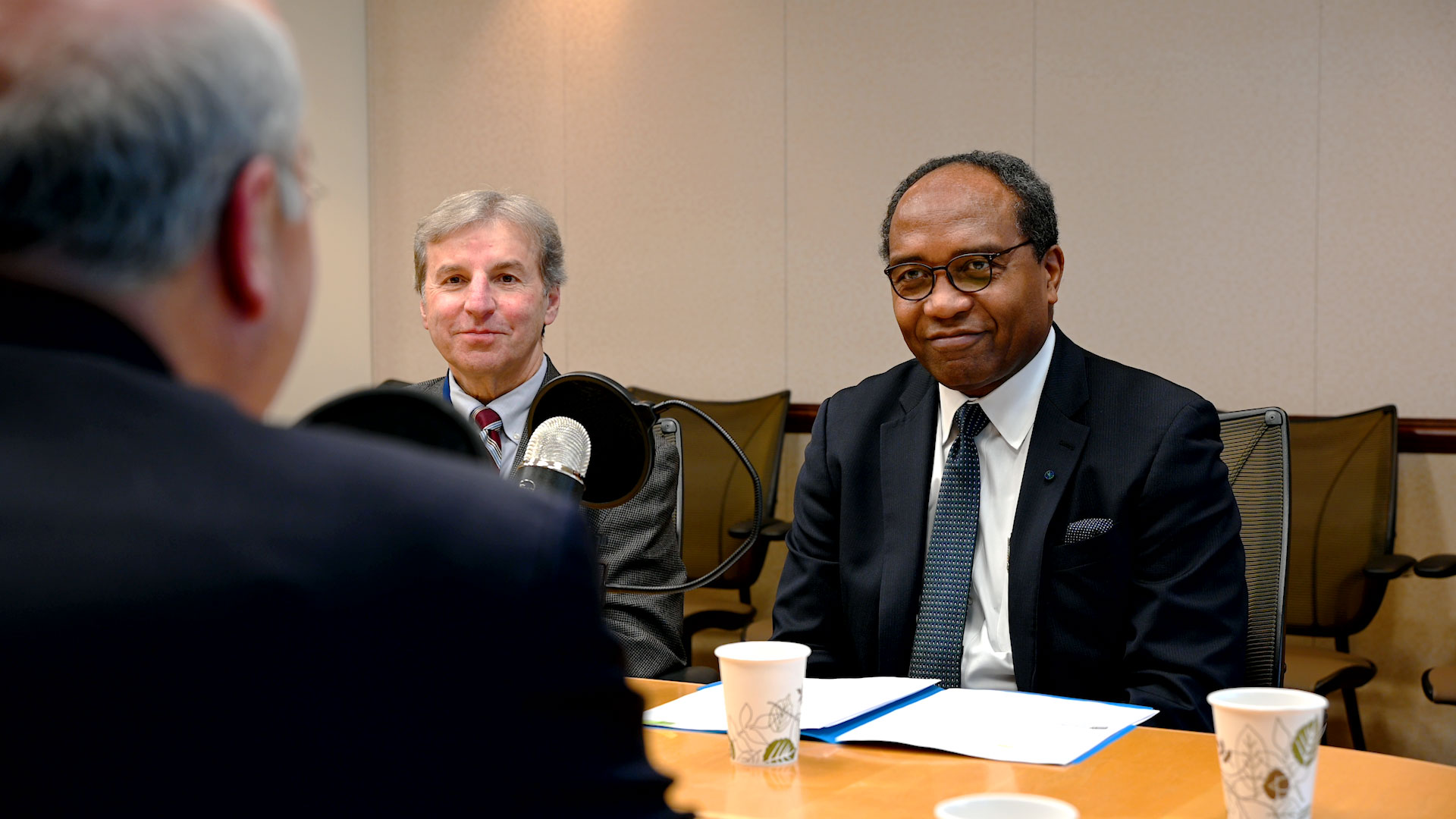 Drs. Cefalu and Rodgers sitting at a table in front of a microphone