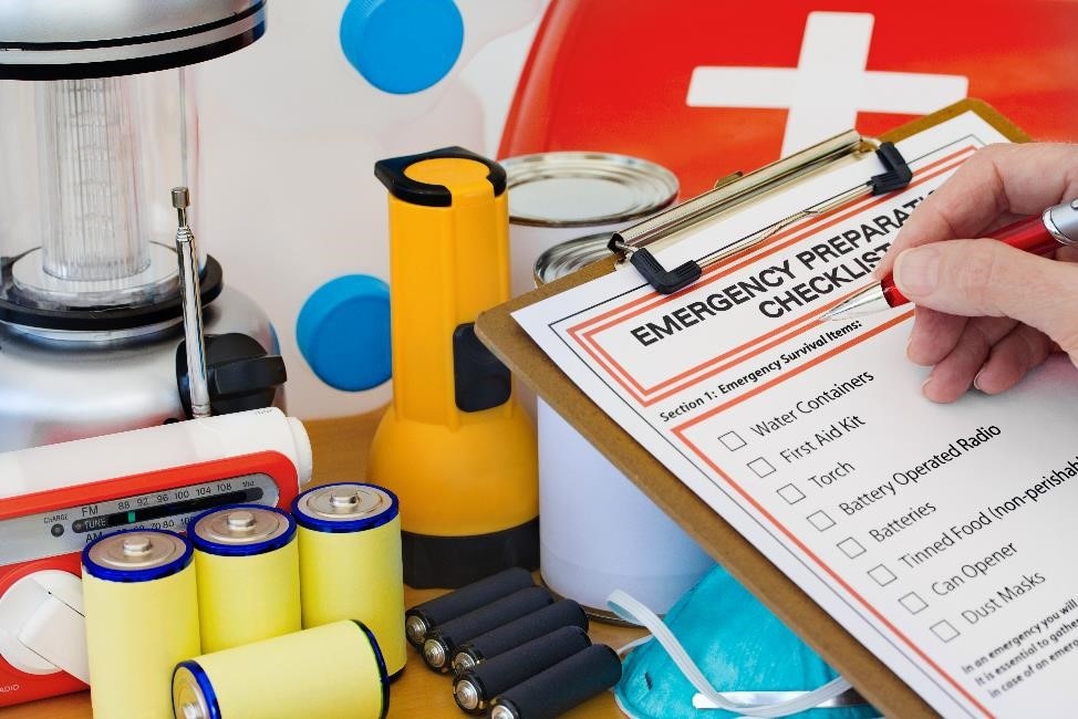 Someone filling out a preparedness checklist with extra supplies in the background.
