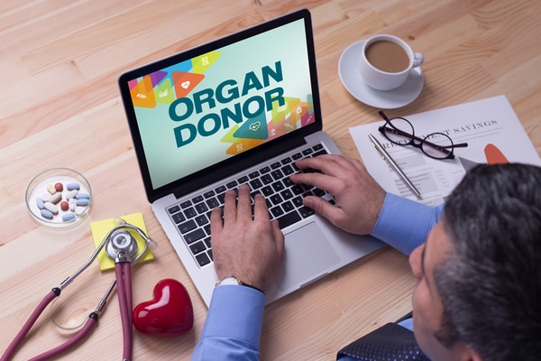 A man using a laptop with the words “organ donor” on the screen.