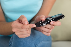 A woman holding a glucometer on her finger.