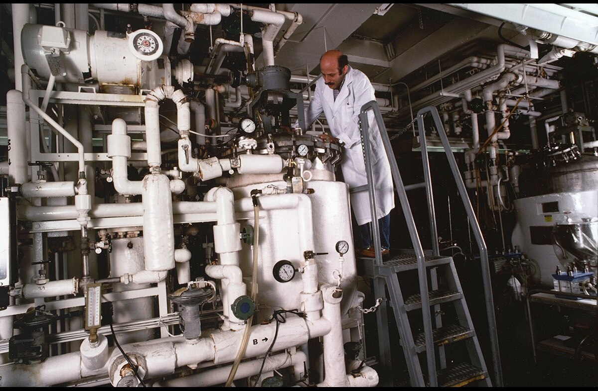 Male doctor standing on ladder next to Biotechnology Core facility equipment.