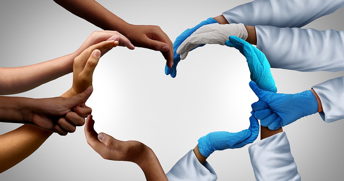 Multicultural hands, some with healthcare coats and gloves, joining together to form a heart