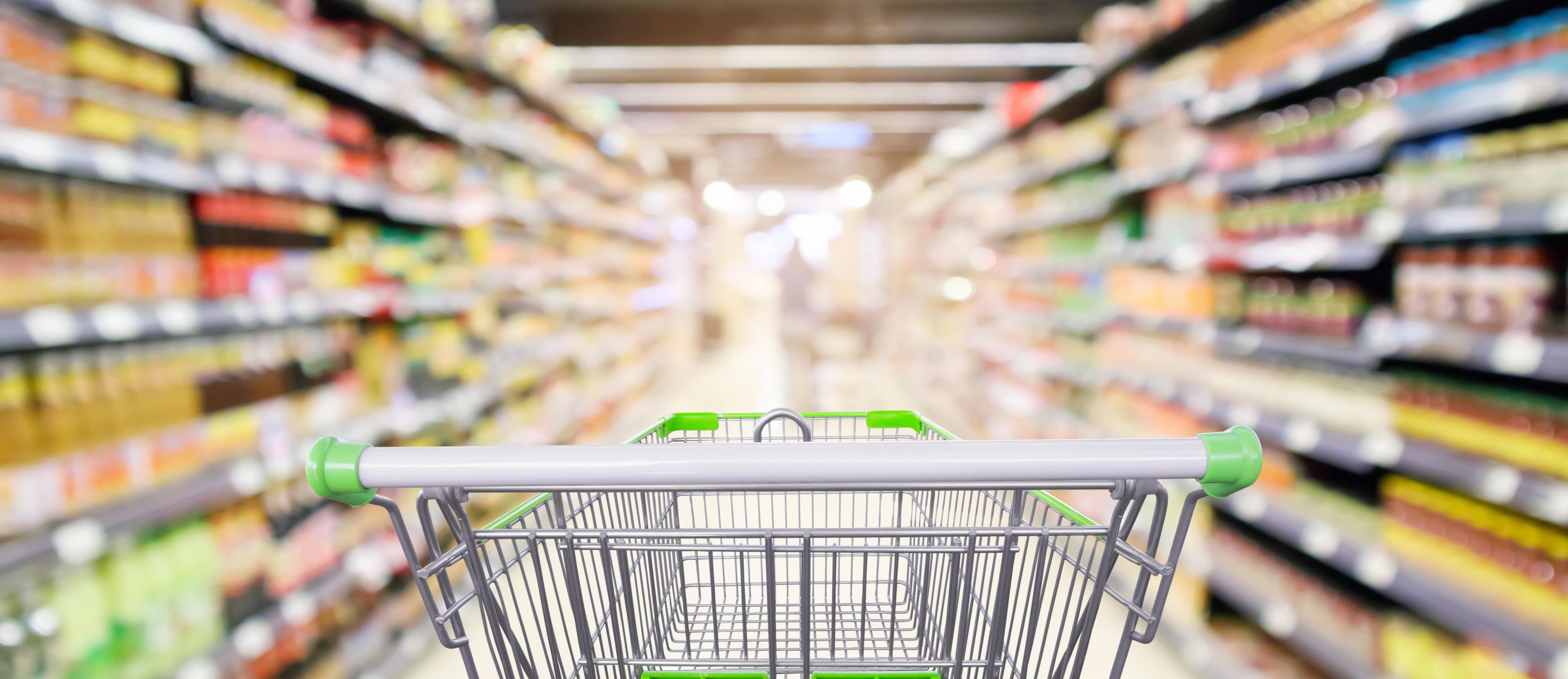 Empty shopping cart in grocery store aisle.