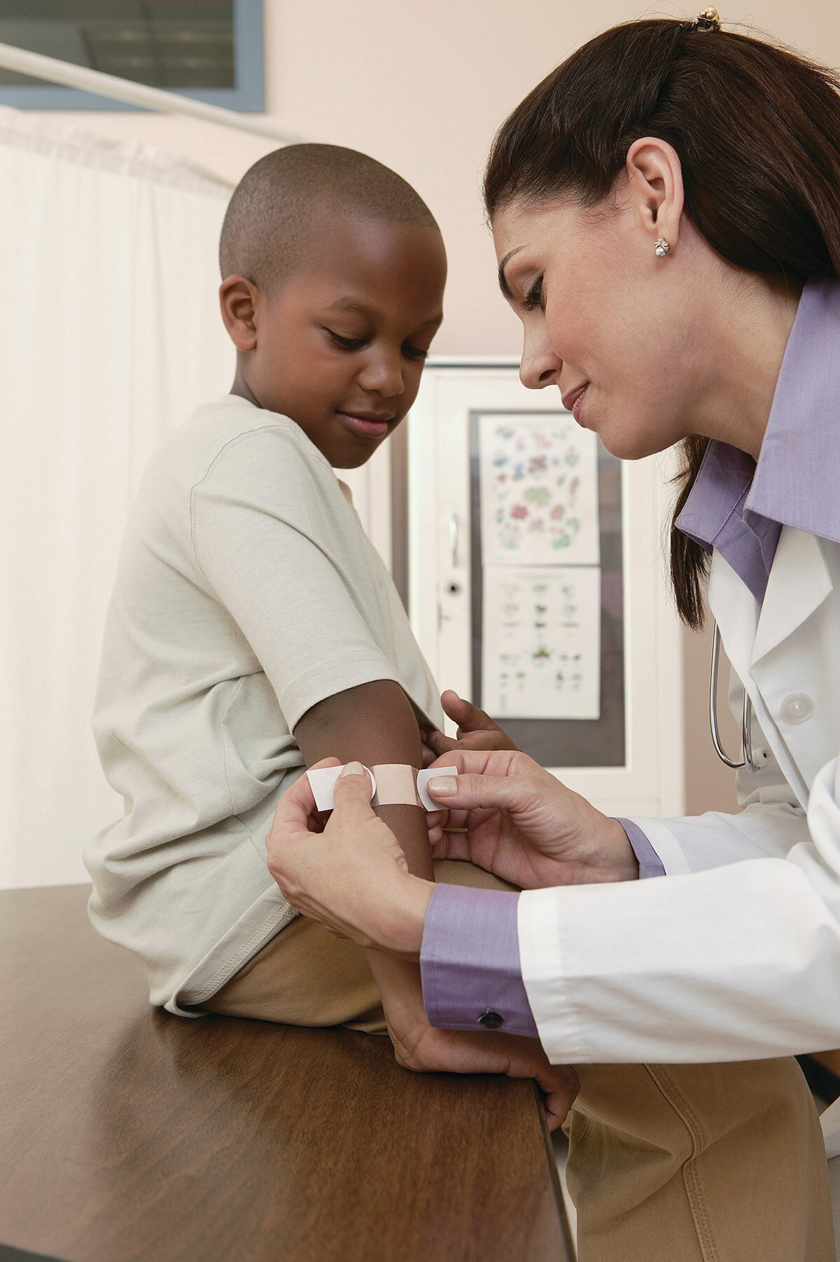 A doctor putting a Band-Aid on a boy's arm.