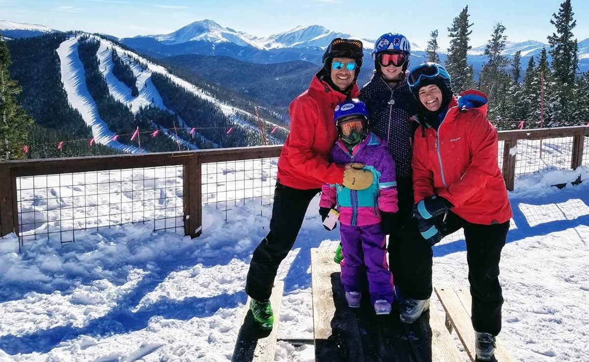 The Ketchum family on a ski trip with snowy mountains behind them