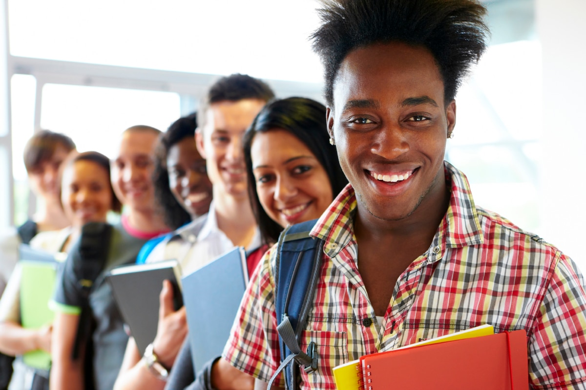  Diverse teens with backpacks and holding notebooks.