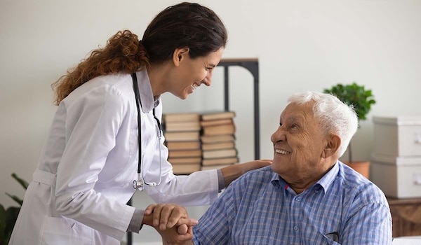 A doctor and older patient smiling and holding hands.