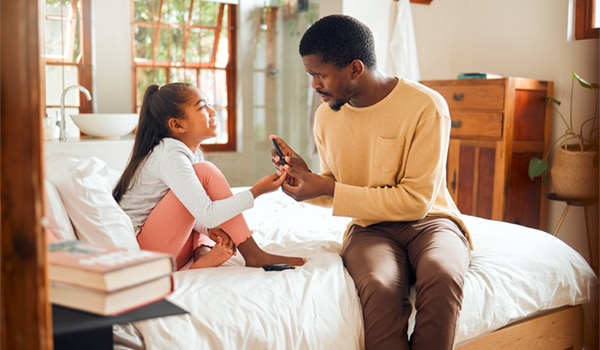 A father helping his doctor check her glucose levels