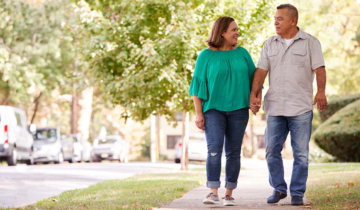 A man and woman walking on a sidewalk.