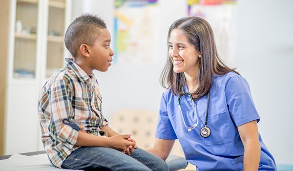 Child sitting on table talking with nurse