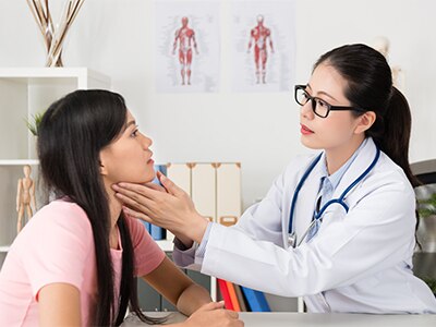 A doctor checking a patient's thyroid.