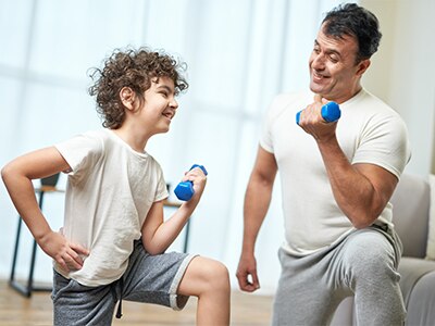 Boy and adult man strength training in living room.