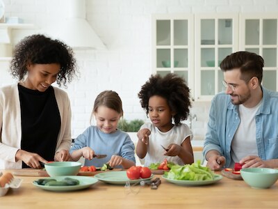 Parents and their children preparing a healthy meal together.