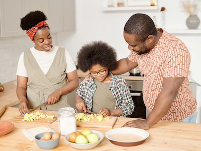 A family cutting up apples in the kitchen.