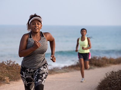 Two women running on a path along the beach