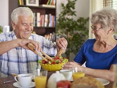 An elderly couple eating a healthy meal together. 