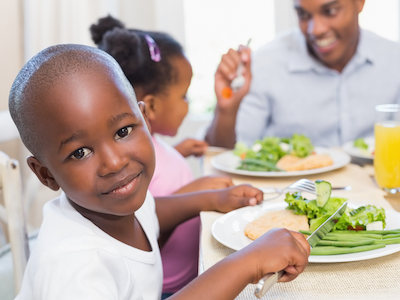A child eating dinner with their family.