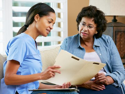 A nurse discussing health information with an older patient at a home visit.