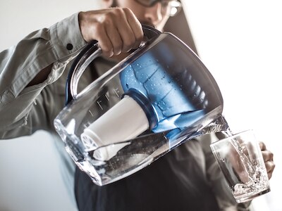 A man pouring filtered water into a glass.