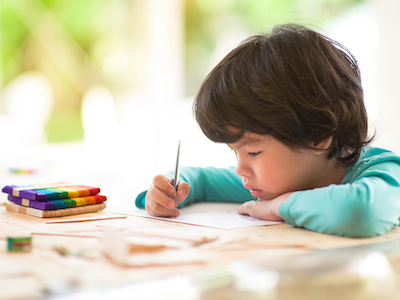 A boy writing on a desk.