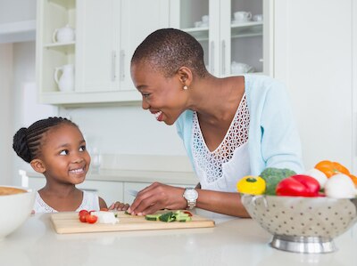 A mother and daughter with vegetables in the kitchen.