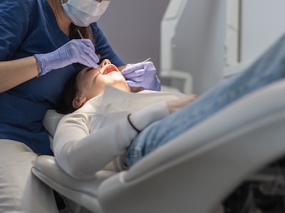 A dentist conducts a deep cleaning and examines a patient's gums.