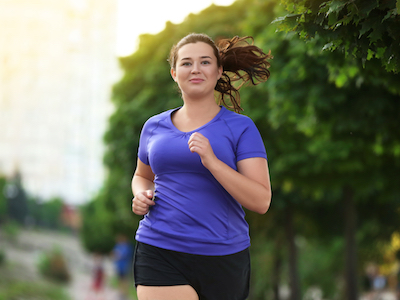 An overweight young woman smiling and jogging