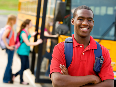 Teenager smiling in front of a school bus