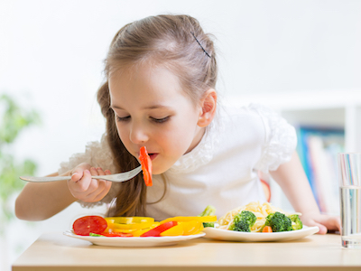 Young girl eating vegetables.