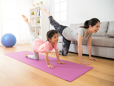 A woman and her daughter exercising at home.
