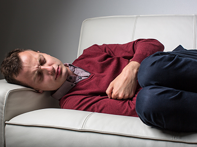 Man lying on a couch with his knees bent and his arms folded across his stomach