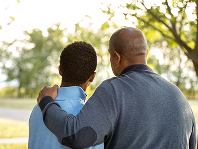 Father with arm around son outdoors